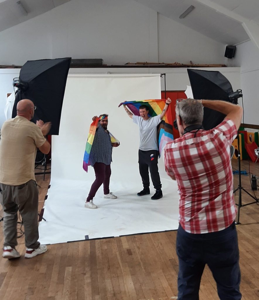 Two people with Pride flags having their photos taken